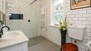 A bathroom with white subway tiles, a white sink, a toilet, and a shower with a glass door.