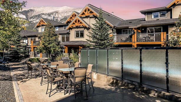 A resort with multiple buildings, outdoor seating, and a mountain backdrop.
