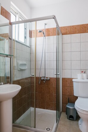 Un baño con cabina de ducha de vidrio, un lavabo blanco y un inodoro.