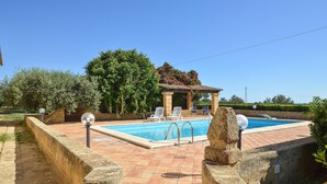 A swimming pool with a pergola, lounge chairs, and a stone wall. - Lovely home in Castelvetrano (Castelvetrano)
