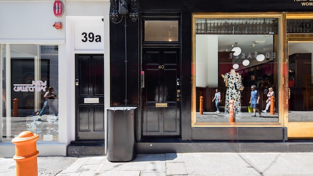 Une devanture de magasin avec une façade noire, une grande vitrine et un hydrant d’incendie bien visible.