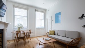Un salon moderne avec un plancher en bois, un canapé, une table basse et un coin repas comprenant des chaises et une table.