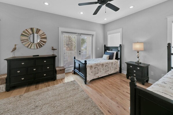 A bedroom with a bed, dresser, nightstand, and a ceiling fan.