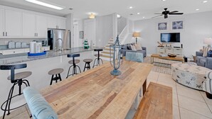 Una cocina moderna con armarios blancos, un refrigerador de acero inoxidable y una barra con taburetes.