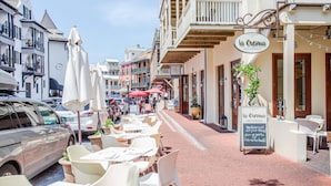 Una calle con terrazas, un café y coches estacionados.