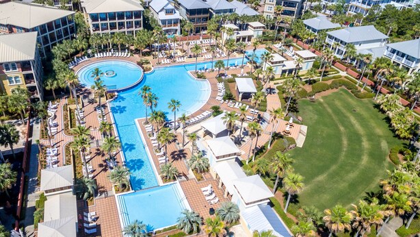 An aerial view of a resort with multiple swimming pools, palm trees, and resort buildings.