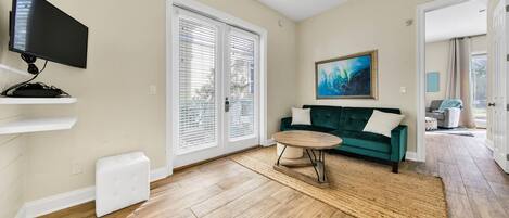 Un salon avec un canapé vert, une table basse ronde et un téléviseur posé sur un meuble.