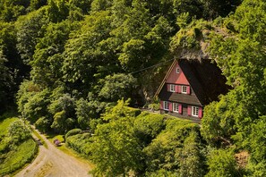 Una casa ubicada en zona boscosa con un camino de tierra que la lleva.