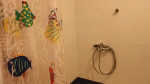 A bathroom with a shower curtain featuring fish designs, a bathtub, and a wall-mounted faucet. - Mandola Studios - Garden view Studio (Kefalonia)