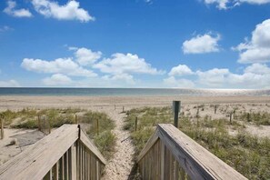 A wooden boardwalk leading to a beach with a clear sky.