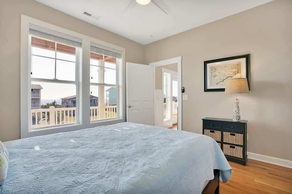 A bedroom with a bed, a nightstand, a lamp, a framed map on the wall, and a view through a door.