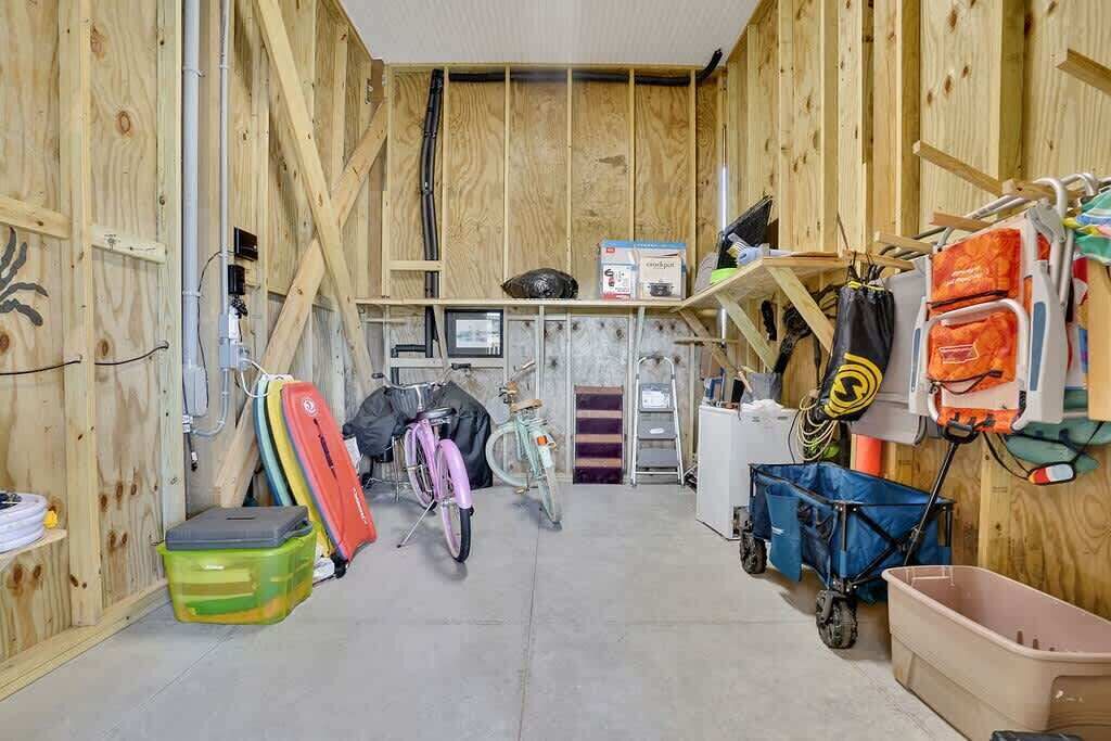 A utility room with wooden walls, a bicycle, a small desk, and various storage items.