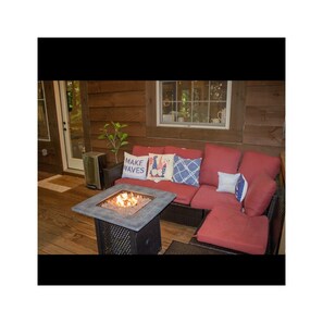 A cozy outdoor seating area with a fire pit and a red sofa with decorative pillows.