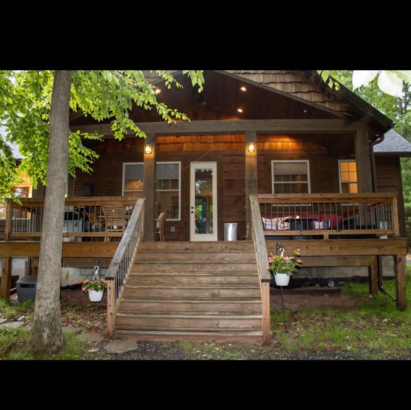 A wooden cabin with a front porch, a staircase, and a railing.