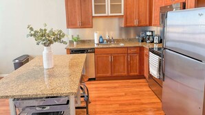 A kitchen with wooden cabinets, a granite countertop, a stainless steel refrigerator, and a dishwasher. - Apartment near Kerrytown Concert House (Ann Arbor)