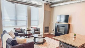 A modern living room with a sofa set, coffee table, fireplace, and a TV mounted on the wall.