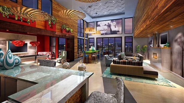 A spacious hotel lobby with a modern design, featuring a large seating area, a bar, and a view of the cityscape through large windows.