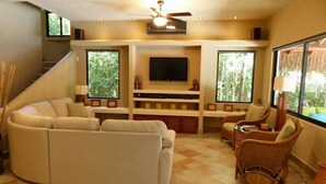 A living room with a sofa, wicker chairs, a flat-screen TV, and a staircase. - Private Villa w/Pool Heat option Near Akumal/Tulum (Akumal)