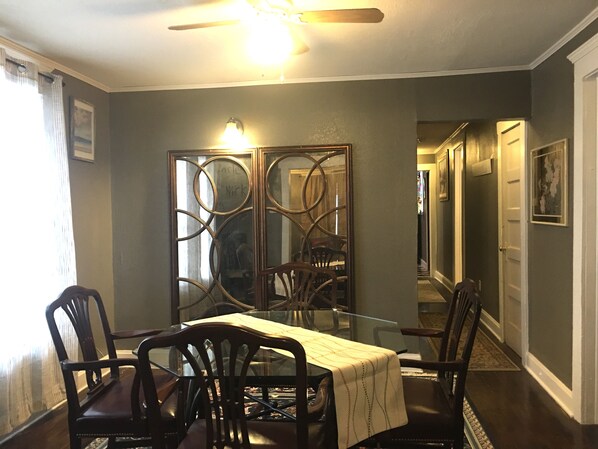 A dining area with a glass table, dark wooden chairs, a decorative metal partition, and a ceiling fan. - 2Bed/2Bath Duplex 2nd Floor House, 6 min. Med.Ctr., 7min.Downtown (Kansas City)