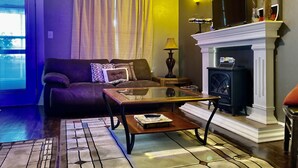 A living room with a sofa, coffee table, fireplace, and a television.