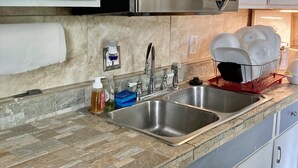 A kitchen with two stainless steel sinks, a microwave, and white cabinets.