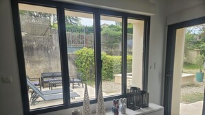 Een kamer met een groot raam, een witte console tafel en uitzicht op een terras.
