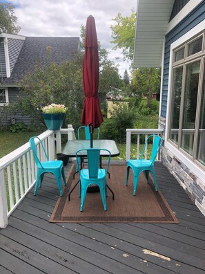 A deck with a table and chairs, a red umbrella, and a potted plant. - Heavenly Lakeside Retreat (East Jordan)