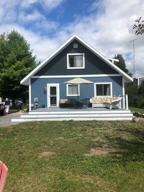 A two-story house with a front porch, a small deck, and a patio area. - Heavenly Lakeside Retreat (East Jordan)