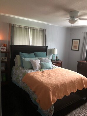 A bedroom with a bed, a nightstand, a lamp, a ceiling fan, and a framed picture on the wall. - Heavenly Lakeside Retreat (East Jordan)