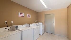 A laundry room with multiple washers and dryers, a door, and signs indicating no boots or shoes and specific washing and drying times. - Studio, 1 King Bed, Kitchenette - Non-Smoking (Baton Rouge)