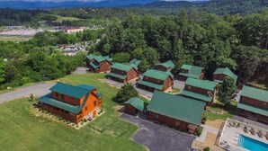 A lodge with multiple cabins, a swimming pool, and a scenic mountainous backdrop.