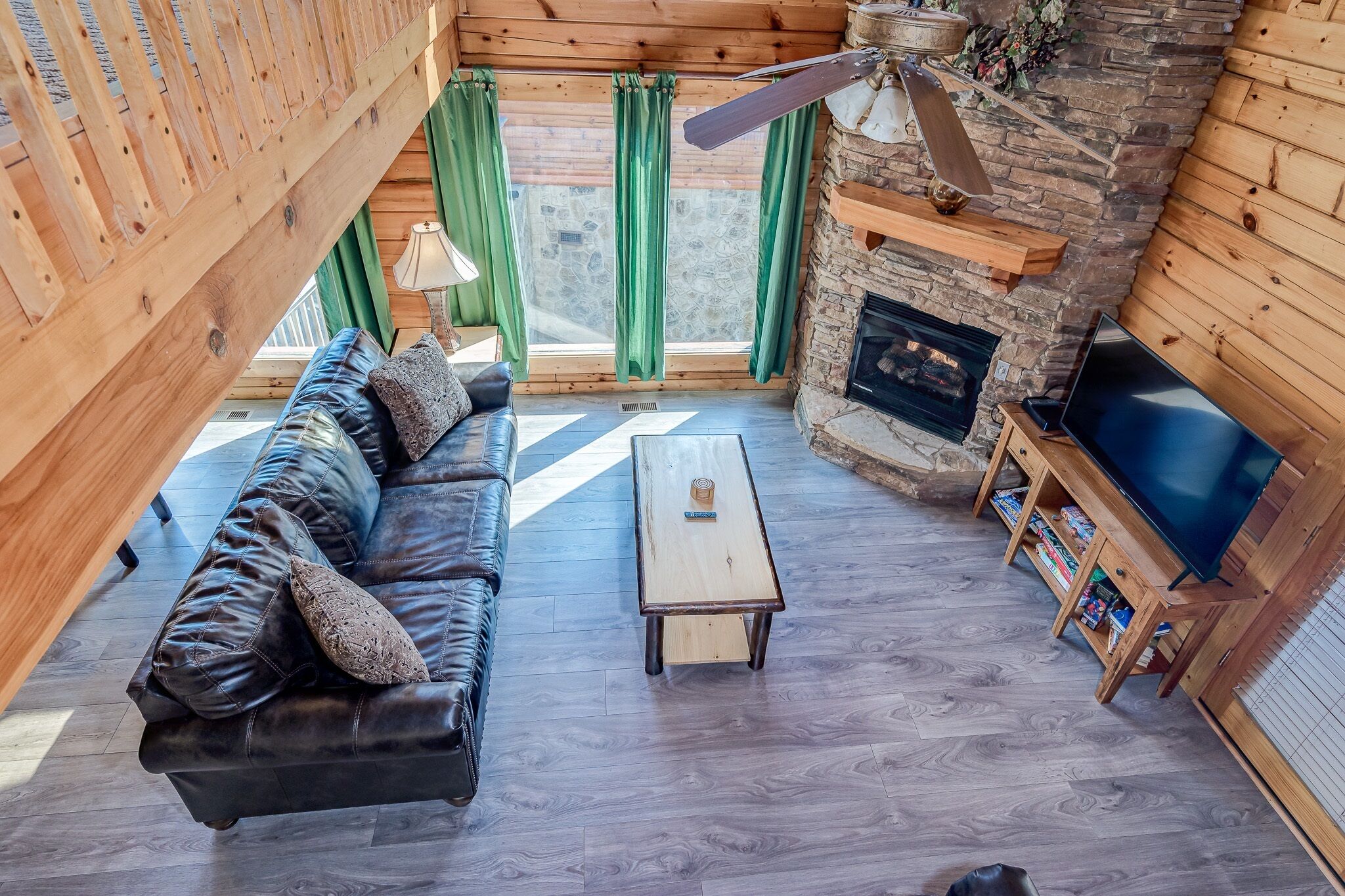 L’intérieur chaleureux d’un chalet avec un canapé en cuir, une table basse en bois, une cheminée et un téléviseur.