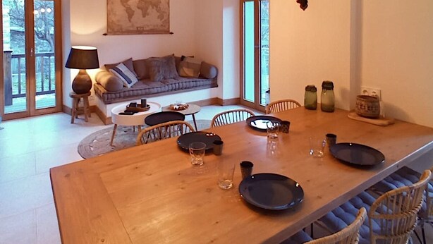 A spacious dining area with a long wooden table, wicker chairs, and a rustic ceiling with exposed beams. - Village house, sleeps 8.  (Saint-Chaffrey)