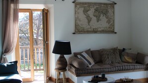 A living room with a sofa, a lamp, a coffee table, and a world map on the wall. - Village house, sleeps 8.  (Saint-Chaffrey)