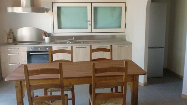 A kitchen with a wooden table and chairs, a stove, and cabinets. - Tourist House San SIsto (Sandrigo)