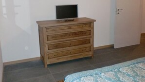 A bedroom with a wooden dresser, a television on top, and a bed with a patterned bedspread. - Tourist House San SIsto (Sandrigo)