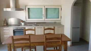 A kitchen with a wooden table and chairs, a stove, and cabinets.