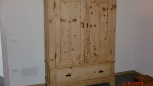 A wooden wardrobe with two doors and a drawer, placed against a white wall. - Tourist House San SIsto (Sandrigo)