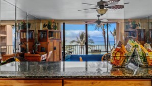 A kitchen with a view of the ocean, a ceiling fan, and a dining area with a view. - Check out our Summer Discounts and Fantastic Views! (Lahaina)