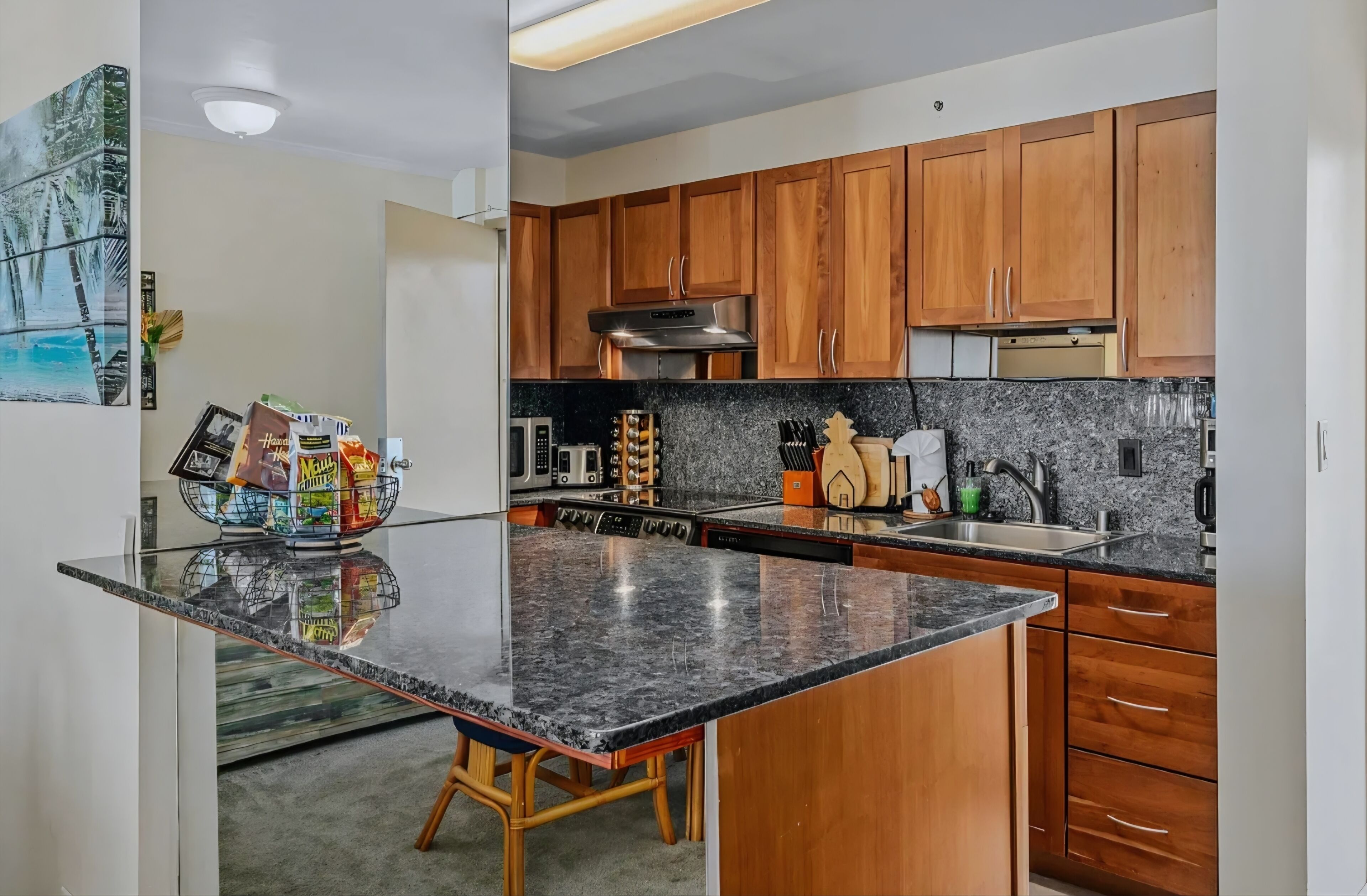 A kitchen with wooden cabinets, a granite countertop, and various appliances.