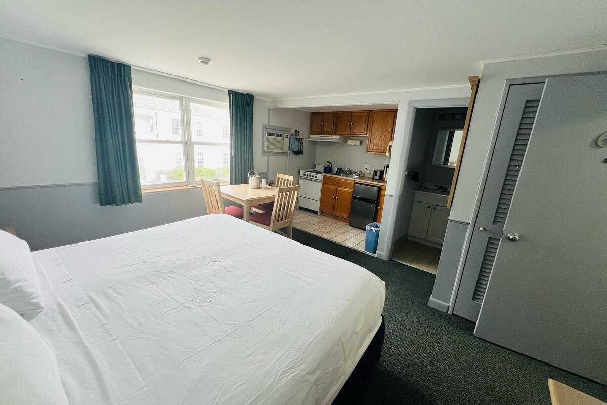 A hotel room with a bed, a desk, and a kitchenette.