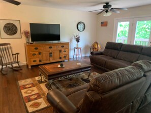 A living room with a leather sofa, a wooden coffee table, a television, and a globe on a stand.