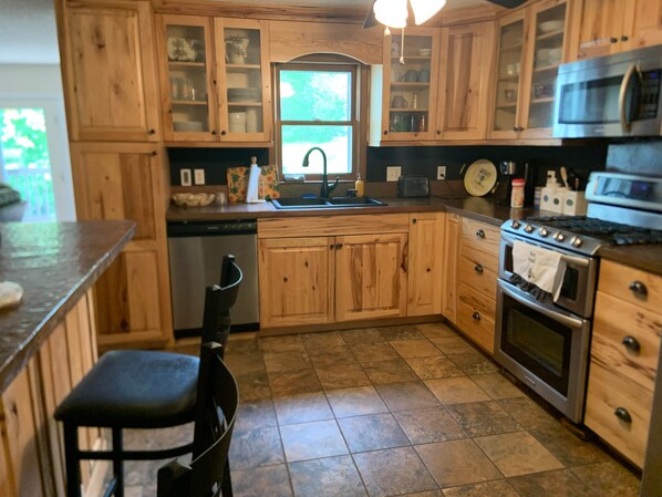 A kitchen with wooden cabinets, a dishwasher, a stove, and a window.