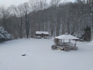 A snow-covered landscape with a cabin and a gazebo in the foreground.
