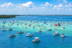 Una marina con numerose imbarcazioni, acqua turchese cristallina e sullo sfondo la silhouette di una città.