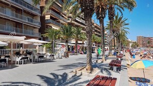 A beachfront promenade with outdoor seating, palm trees, and a beach area with umbrellas. - 2 Bed Apartment with pool, within a short walk to the beach in Torrevieja (Torrevieja)