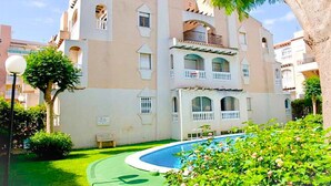 Un edificio de varios pisos con piscina, balcones y un jardín bien cuidado.