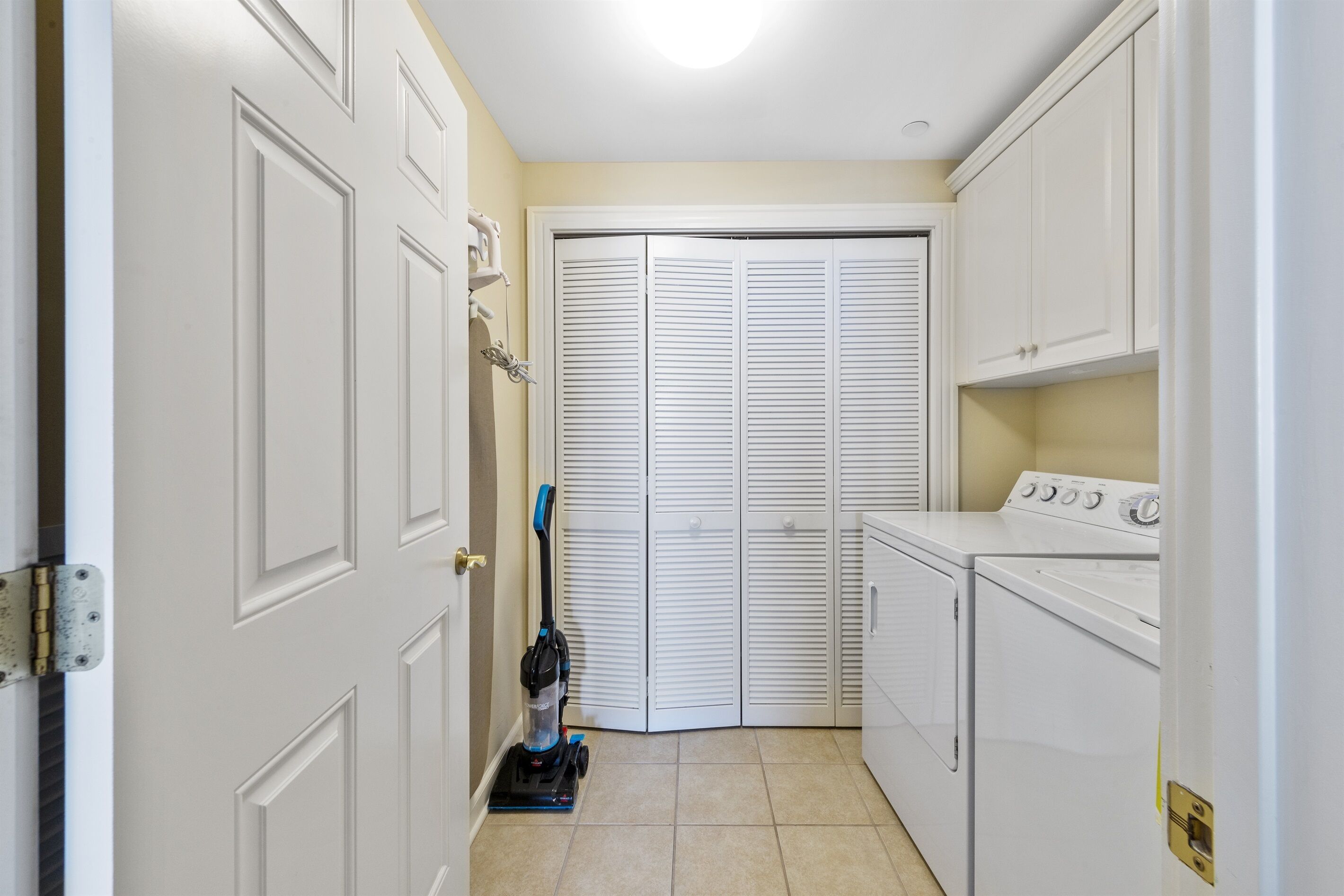 A laundry room with a washing machine, dryer, and a vacuum cleaner.