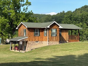 A wooden house with a stone foundation, a covered porch, and a wooden deck.
