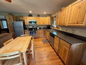 A compact kitchen with wooden cabinets, a microwave, an oven, a refrigerator, and a dishwasher.